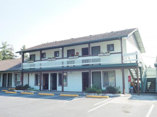 a large white building with a balcony and a parking lot at Wild Rivers Motorlodge in Brookings