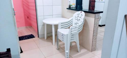 una cocina con 2 sillas blancas y una mesa en Casa de temporada em Petrolina-pe en Petrolina