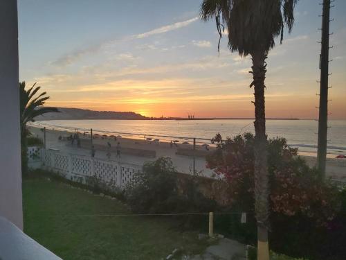 - une plage au coucher du soleil avec des personnes qui s'y promènent dans l'établissement la belle vue tanger R, à Tanger