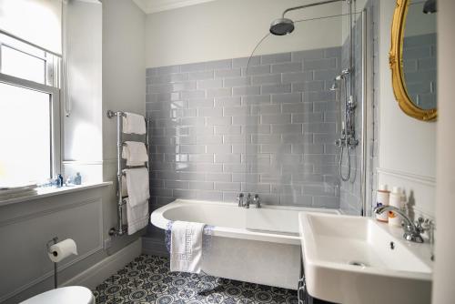 La salle de bains blanche est pourvue d'une baignoire et d'un lavabo. dans l'établissement The Eastleigh, à Seaton