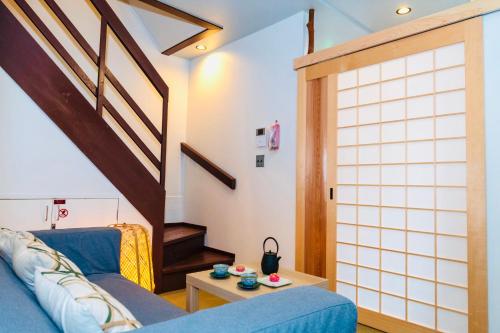 a living room with a blue couch and stairs at Nishihan in Kyoto