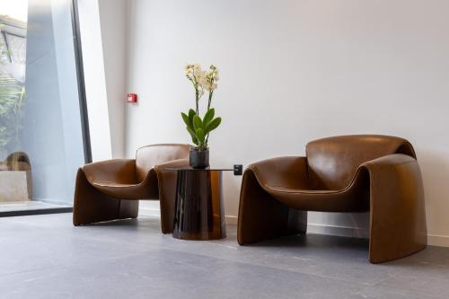 two leather chairs and a table with a vase on it at DIAGONAL HOTEL in Tangier