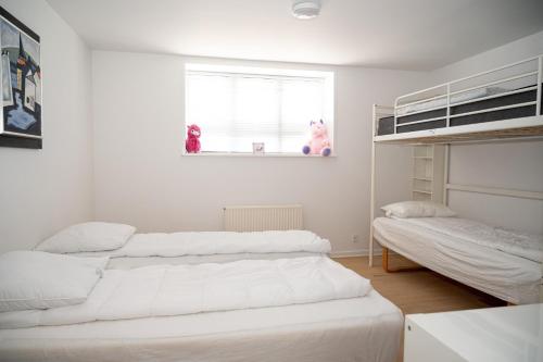 1 dormitorio blanco con 2 camas y ventana en 5 minute walk to LEGO house - 2 bedrooms 80m2 apartment with garden, en Billund