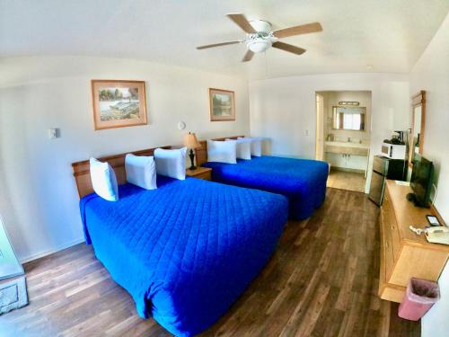 a bedroom with two blue beds and a ceiling fan at Wild Rivers Motorlodge in Brookings