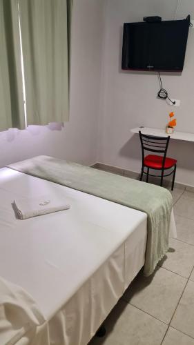 a bedroom with a bed and a chair and a television at Dom Pablo Hotéis in São José dos Pinhais