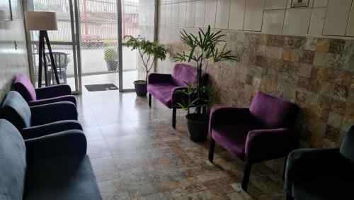 a waiting room with purple chairs and potted plants at Dom Pablo Hotéis in São José dos Pinhais