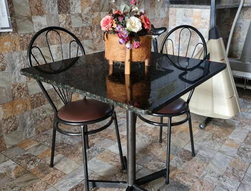 a black table with two chairs and a vase of flowers at Dom Pablo Hotéis in São José dos Pinhais