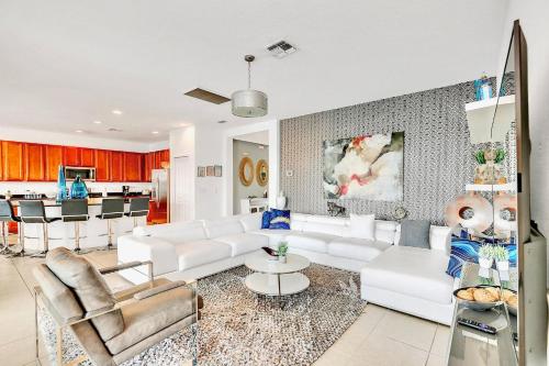 a living room with white furniture and a kitchen at 6BR Luxury Home w Pool Hot Tub and Games room in Kissimmee