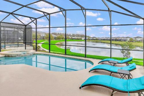 a swimming pool with blue chairs and a large glass house at 6BR Luxury Home w Pool Hot Tub and Games room in Kissimmee