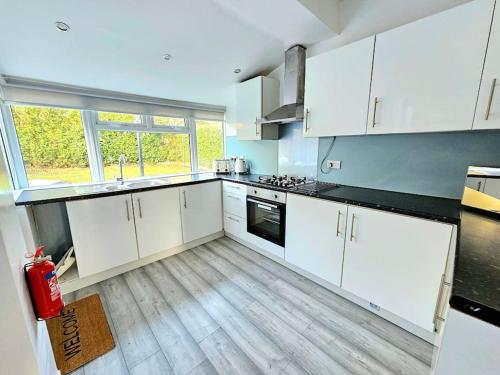 een keuken met witte kasten en een groot raam bij Spacious Haven with Free Parking in Glasgow