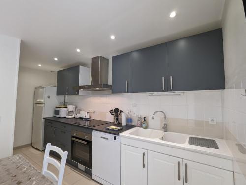 une cuisine avec des armoires blanches et des appareils noirs dans l'établissement Maison de Bourg Rénovée avec Jardin et Salle de Jeux à Levroux - FR-1-591-204, à Levroux