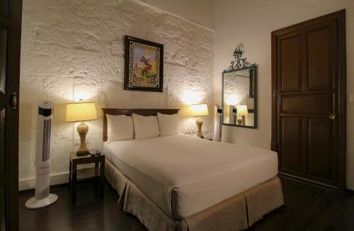 a bedroom with a bed with two lamps and a door at Hotel Casino Morelia in Morelia