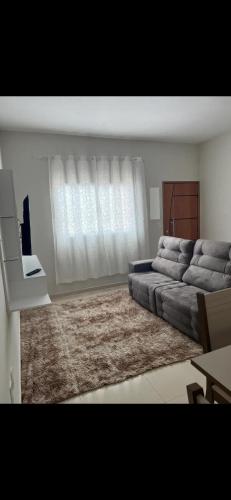 een woonkamer met een bank en een tapijt bij Apto Nossa Senhora Aparecida in Aparecida