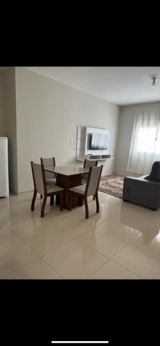 een woonkamer met een tafel, stoelen en een bank bij Apto Nossa Senhora Aparecida in Aparecida
