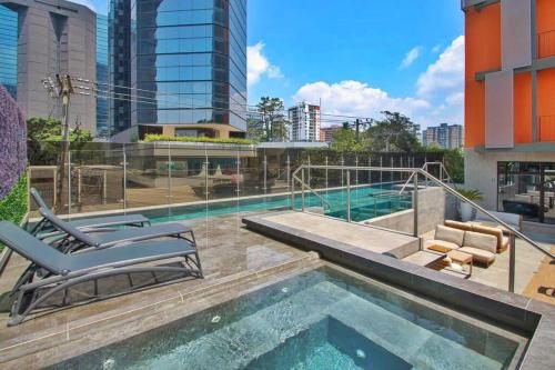 a swimming pool with two lounge chairs next to a building at Deluxe Apto Guatemala zona 10 Edificio EON in Guatemala