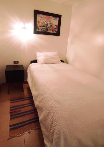 Un dormitorio con una cama blanca con una luz en la pared en ANDAHUAYLAS CENTRO, en Andahuaylas