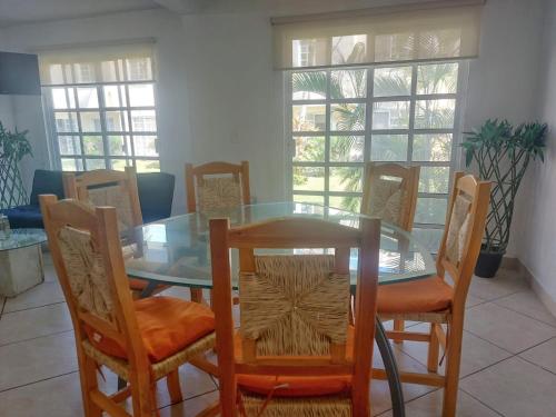 a dining room with a glass table and chairs at Casa Azur- vista al mar y alberca in Acapulco