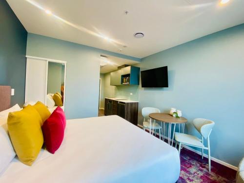 a bedroom with a large white bed with colorful pillows at La Quinta by Wyndham Parnell Auckland in Auckland