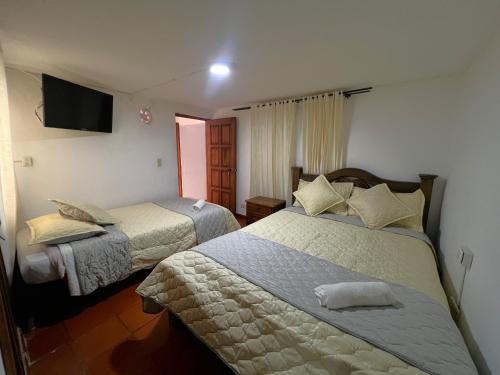 a bedroom with two beds and a flat screen tv at Anhyali Hospedaje in Villa de Leyva