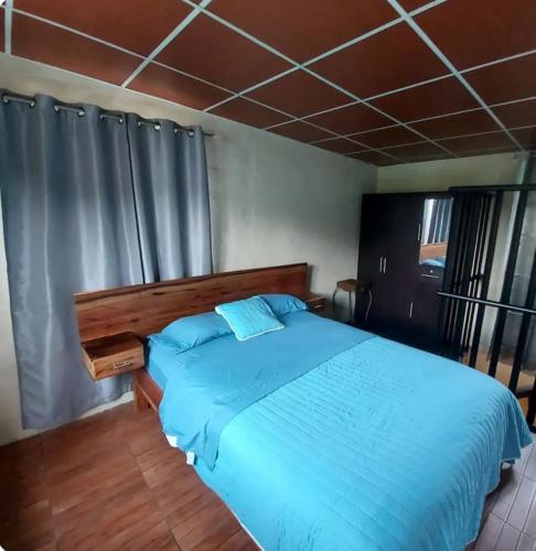 een slaapkamer met een bed met een blauw dekbed bij Descanso en ensenada in Estelí