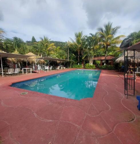 een zwembad in een resort met palmbomen op de achtergrond bij Descanso en ensenada in Estelí