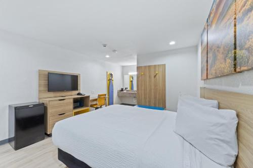 a bedroom with a white bed and a flat screen tv at Days Inn by Wyndham McKinney in McKinney