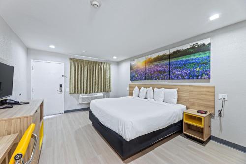a hotel room with a bed and a tv at Days Inn by Wyndham McKinney in McKinney
