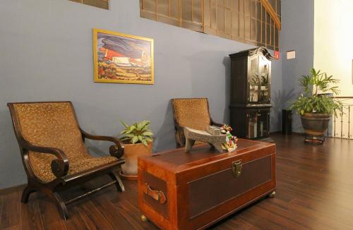 a living room with two chairs and a suitcase at Hotel Casino Morelia in Morelia