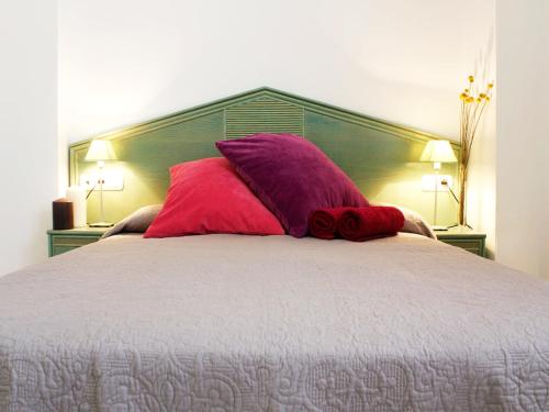 un letto con due cuscini rossi sopra di Apartamentos Amatista Unitursa a Calpe