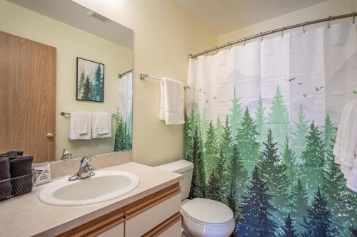 a bathroom with a toilet and a shower curtain with trees at Alpine Paradise in Leavenworth
