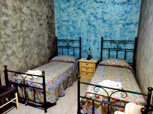 2 camas individuales en un dormitorio con paredes azules en Etna Holiday Apartment - Casa Vacanze en Fiumefreddo di Sicilia