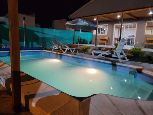ein Pool in der Nacht mit zwei Stühlen und einem Sonnenschirm in der Unterkunft Cabañas La Estrella in Salta
