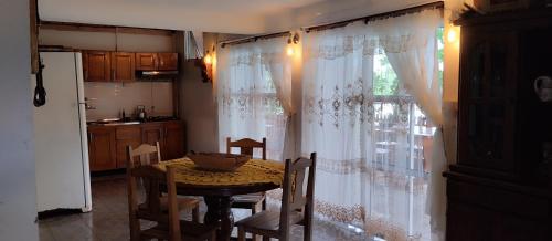 eine Küche mit einem Tisch und ein Fenster mit Vorhängen in der Unterkunft Cabañas Refugio Verde in El Soberbio