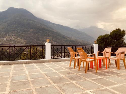 un grupo de sillas sentadas en un balcón con montañas al fondo en Sandeep Restro & Cafe, en Rajkot