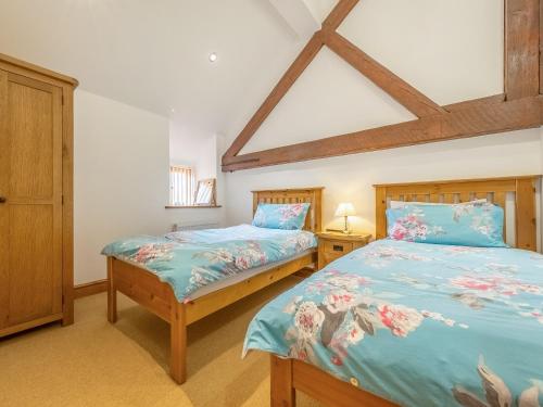 two twin beds in a bedroom with a roof at The Great North Barn - Ukc2526 in Trunch