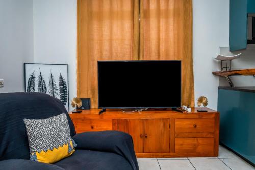 a living room with a television on a wooden dresser at Fare Piafau - Aéroport Faa'a Tahiti in Faaa