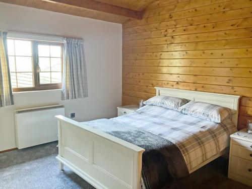 a bedroom with a bed and a wooden wall at Crown Hill Lodge in Cononley