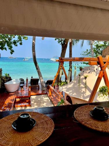 a view of the ocean from a beach with two tables at Natures Edge Beachfront Luxury Glamping Koh Tao in Koh Tao