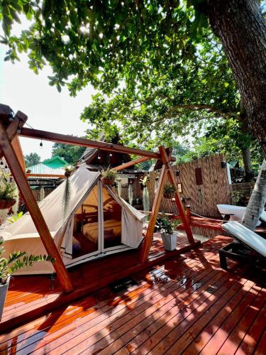 a tent on a deck under a tree at Natures Edge Beachfront Luxury Glamping Koh Tao in Koh Tao