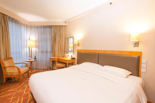 a hotel room with a large bed and a chair at The Harbourview - Chinese YMCA of Hong Kong in Hong Kong