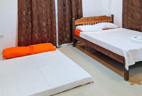 two beds in a room with orange sheets at RedDoorz @ Hergem Siargao Inn in General Luna