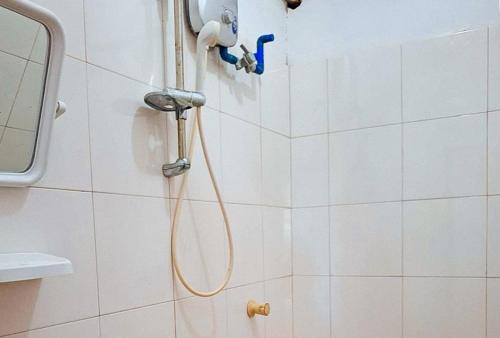 um chuveiro com uma mangueira numa casa de banho em azulejos brancos em RedDoorz @ Hergem Siargao Inn em General Luna