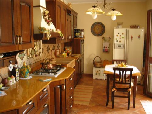 a kitchen with wooden cabinets and a table and a refrigerator at B&B Villa Liliya in Fiumefreddo di Sicilia