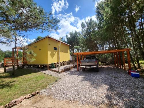 a small yellow house with a truck parked in front of it at LOBOS DEL BOSQUE CON JACUZZi in Punta Del Diablo