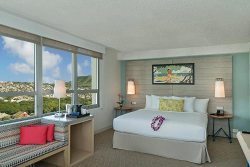 Queen Kapiolani Hotel في هونولولو: غرفة نوم بسرير ابيض ونافذة كبيرة