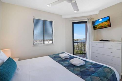a bedroom with a bed and a tv and a window at Nautilus Resort - Private Apartment in Mooloolaba
