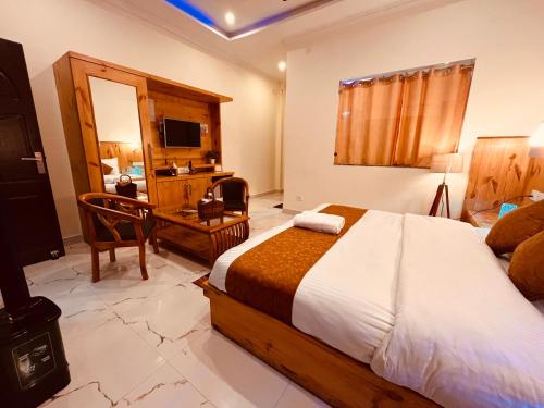 a bedroom with a bed and a desk and a television at Siluswar Hotel in Junagadh