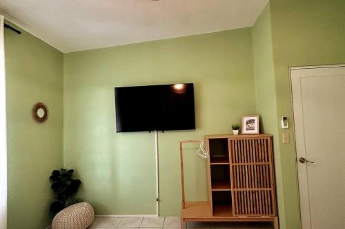a living room with a flat screen tv on a green wall at Casa El Coqui in Luyando