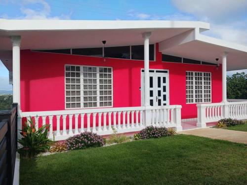 a red house with a white fence in front of it at Casa El Coqui in Luyando