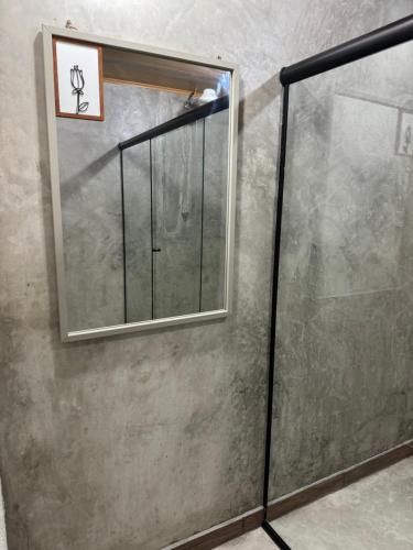 uma porta de duche em vidro com um espelho na parede em Chalé 04 com cozinha no coração de Penedo em Itatiaia